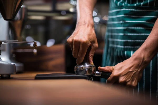 Официант сжимает кофе в кофеварке — стоковое фото