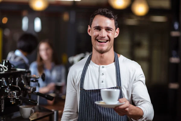 Gülümseyen barista kapuçino holding — Stok fotoğraf