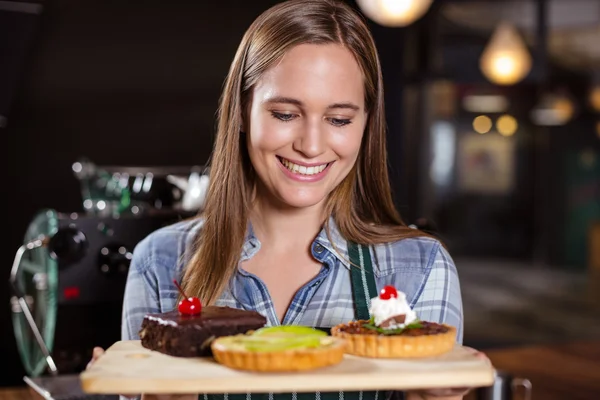 Pretty barista holding desserts — Stock Photo, Image