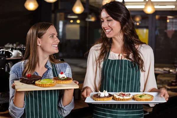 Bonitos baristas segurando sobremesas — Fotografia de Stock