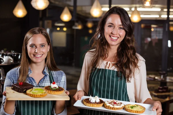 Baristas sonrientes sosteniendo postres —  Fotos de Stock