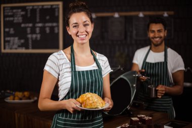 Smiling barista holding croissants clipart