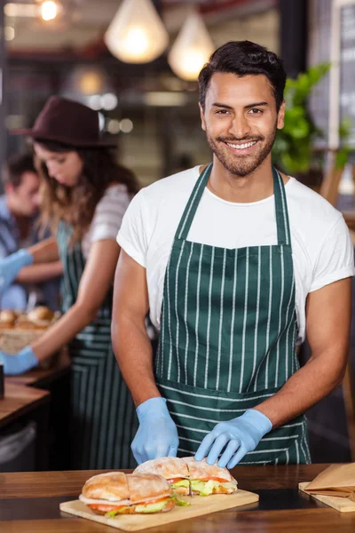 Lachende barista snijden sandwich — Stockfoto