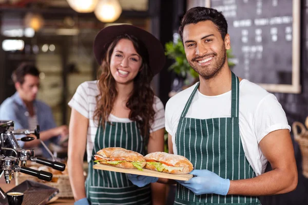 Baristas souriants tenant des sandwichs — Photo