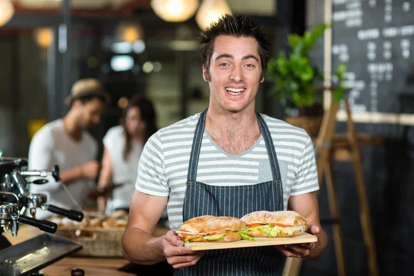 Glimlachend barista holding broodjes — Stockfoto