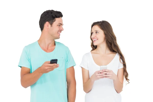 Pareja sonriente usando sus teléfonos inteligentes — Foto de Stock