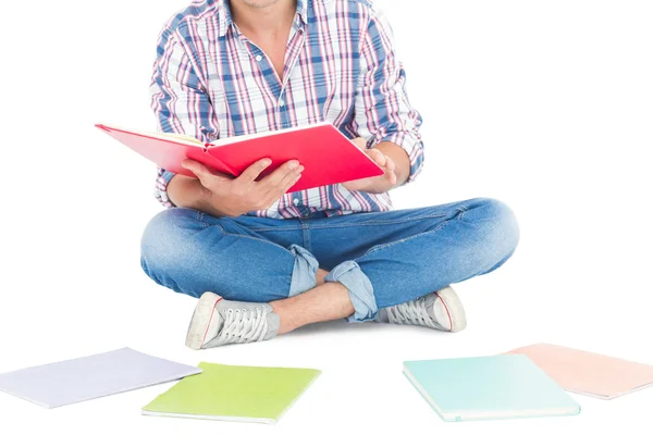 Mann liest ein Buch, während er auf dem Boden sitzt — Stockfoto