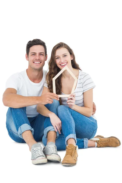 Feliz pareja sosteniendo la forma de casa — Foto de Stock