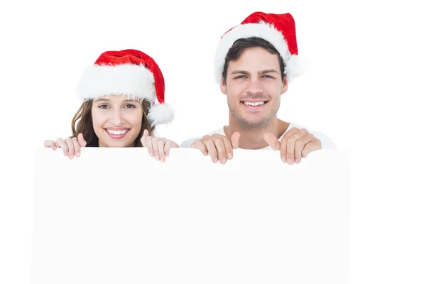 Ευτυχισμένο ζευγάρι με καπέλο santa κρατώντας μια αφίσα — Φωτογραφία Αρχείου