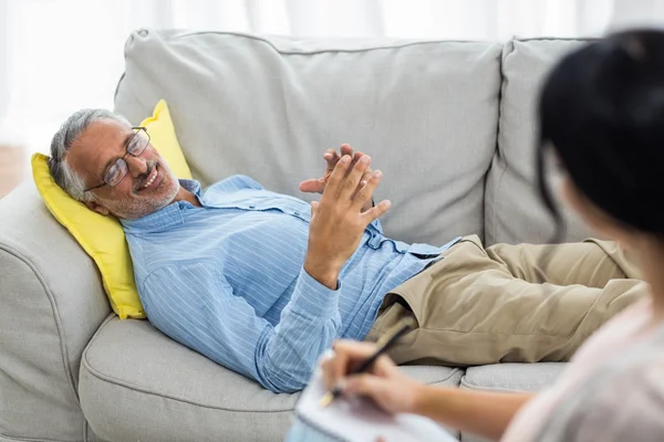 Arzt schreibt auf Notizblock, während er einen Mann konsultiert — Stockfoto