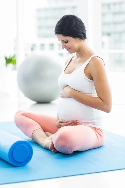 Mulher grávida tocando seu estômago durante o exercício — Fotografia de Stock