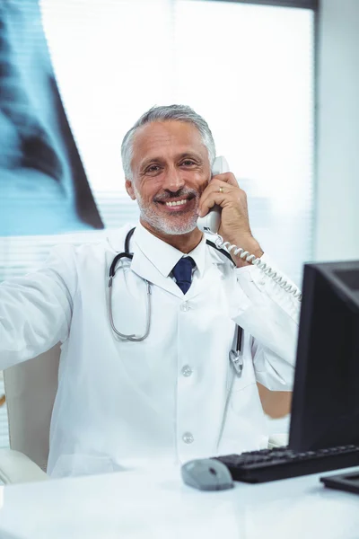 Médico revisando un informe de rayos X mientras habla por teléfono —  Fotos de Stock