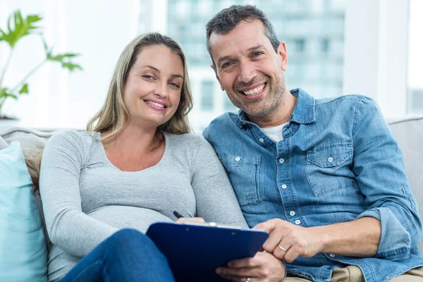 Pregnant woman writing on clipboard — Stock Photo, Image