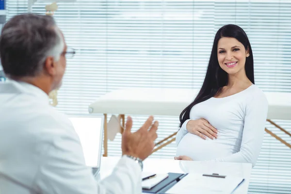 Zwangere vrouw interactie met arts bij kliniek — Stockfoto