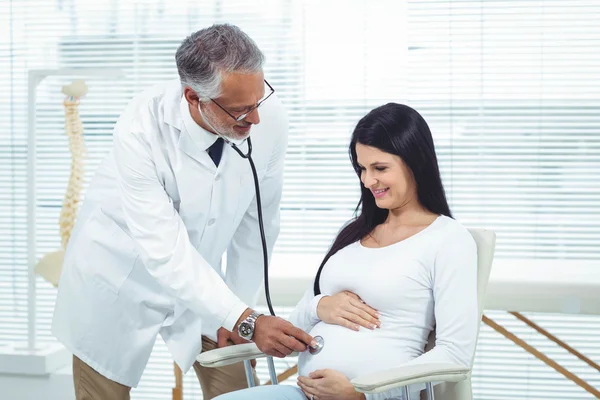 Médico examinando mulher grávida com um estetoscópio — Fotografia de Stock