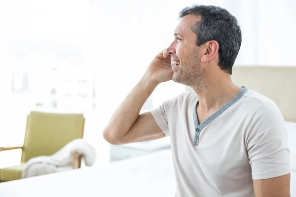 Mann telefoniert im Schlafzimmer mit Smartphone — Stockfoto