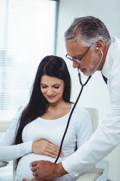 Médico examinando mulher grávida com um estetoscópio — Fotografia de Stock