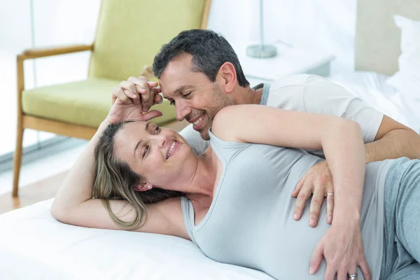 Expecting couple lying on bed and chatting — Stock Photo, Image