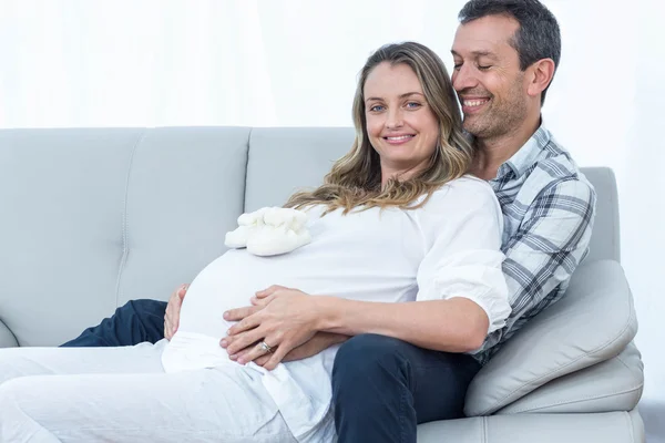Έγκυος ζευγάρι που κάθεται στον καναπέ — Φωτογραφία Αρχείου