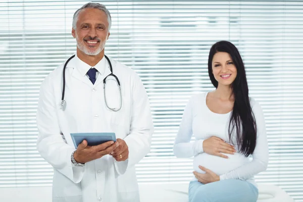 Médico e mulher grávida sorrindo para a câmera — Fotografia de Stock