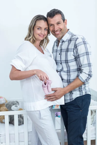 Casal grávida segurando sapatos de bebê — Fotografia de Stock