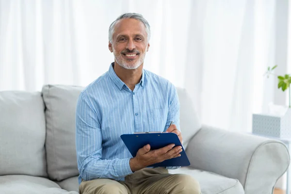 Doctor sitting with a clipboard — Stock Photo, Image