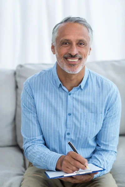 Doctor sitting with a clipboard — Stock Photo, Image