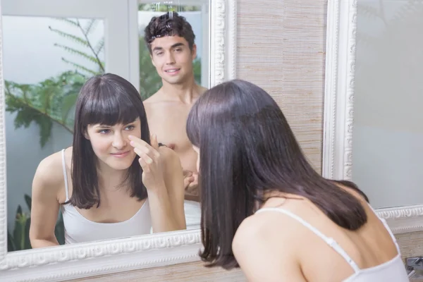 Vrouw op zoek in badkamerspiegel — Stockfoto