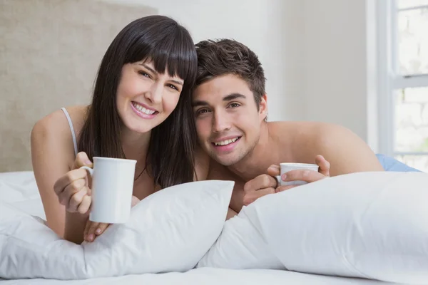 Jovem casal tendo xícara de chá na cama — Fotografia de Stock