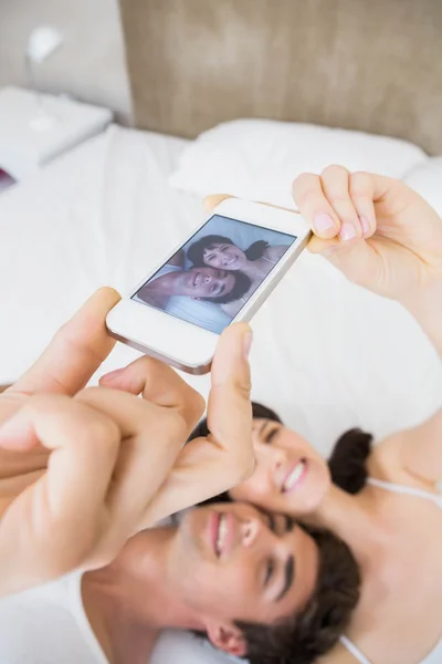 Paar liegt auf Bett und macht ein Selfie — Stockfoto