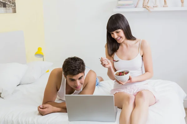 Junges Paar schaut auf Laptop im Bett — Stockfoto