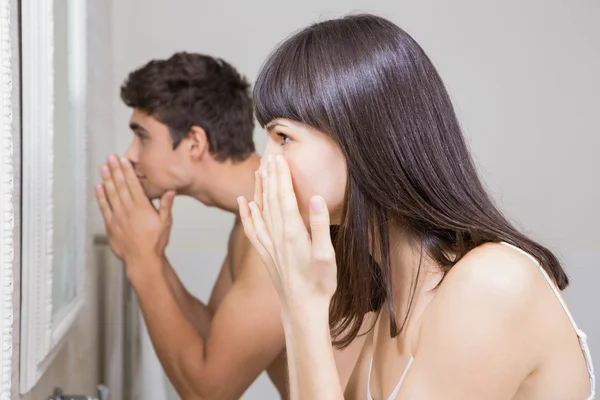 Young couple looking at face in mirror — Stock Photo, Image