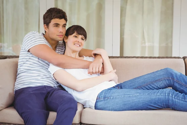 Jovem casal abraçando no sofá — Fotografia de Stock