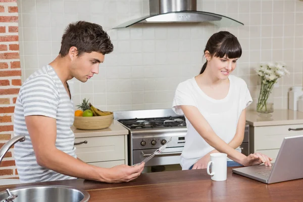 Woman using laptop and man reading newspaper — Stock Photo, Image