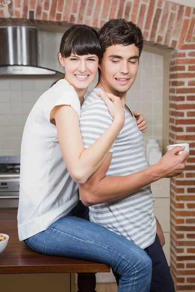 Jovem mulher abraçando o homem na cozinha — Fotografia de Stock