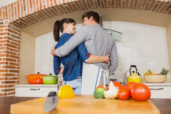 Vegetables on chopping board and couple embracing — Stock Photo, Image