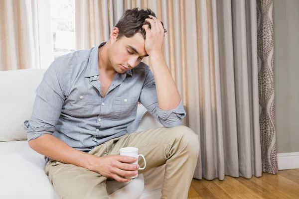 Stressé jeune homme assis sur le canapé — Photo