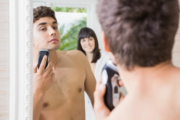 Young man in mirror shaving with electric shaver — Stock Photo, Image