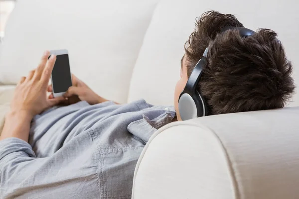 Hombre joven en casa relajándose en el sofá — Foto de Stock