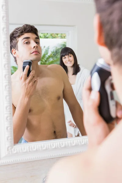 Genç adam ayna tıraş ile Elektrikli tıraş makinesi — Stok fotoğraf