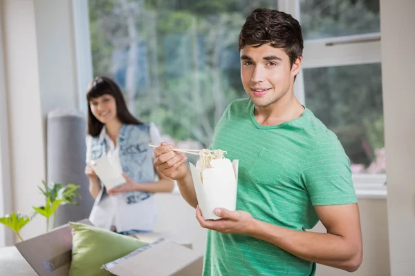 Молодой человек и женщина едят лапшу дома — стоковое фото