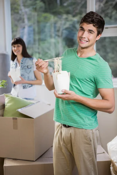 Молодой человек и женщина едят лапшу дома — стоковое фото