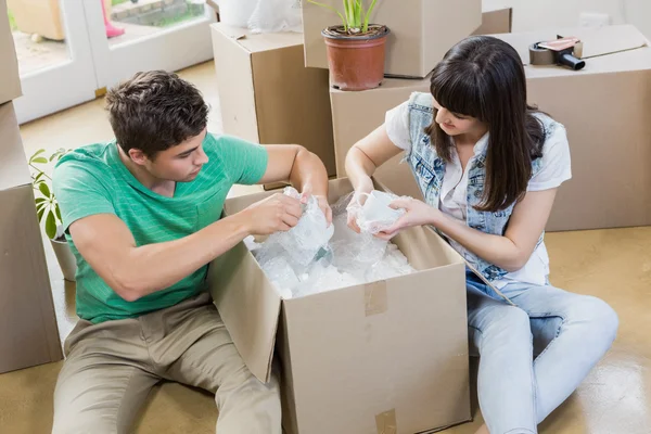 Les jeunes couples déballent des boîtes en carton dans leur nouvelle maison — Photo