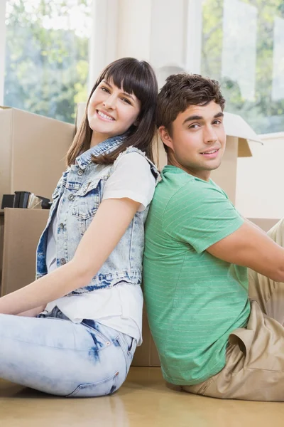 Pareja joven sentados juntos en el suelo y sonriendo — Foto de Stock