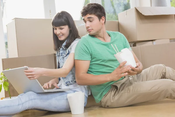 Pareja joven comiendo fideos y usando laptop — Foto de Stock