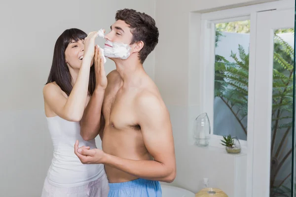 Mujer joven aplicando crema de afeitar en la cara de los hombres jóvenes — Foto de Stock