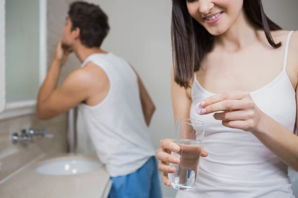 Hermosa mujer poniendo píldora en un vaso de agua — Foto de Stock