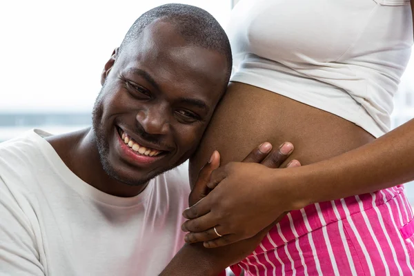Man luisteren naar zwangere dames maag — Stockfoto