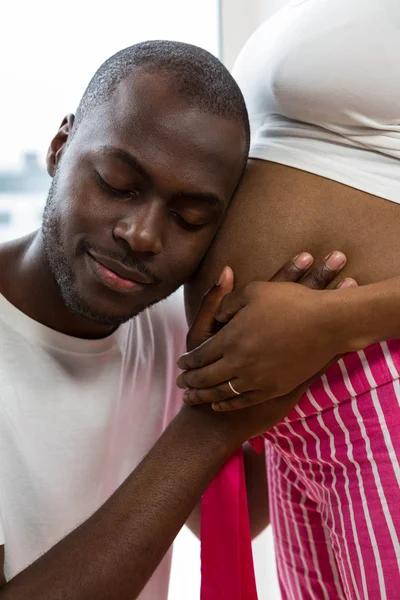 Мужчина слушает беременных женщин желудок — стоковое фото