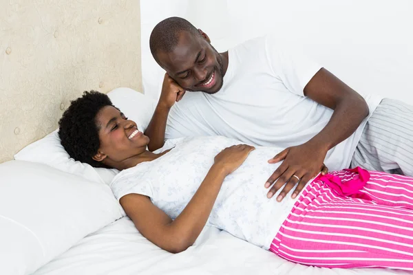 Мужчина касается беременных женщин желудка во время отдыха в постели — стоковое фото